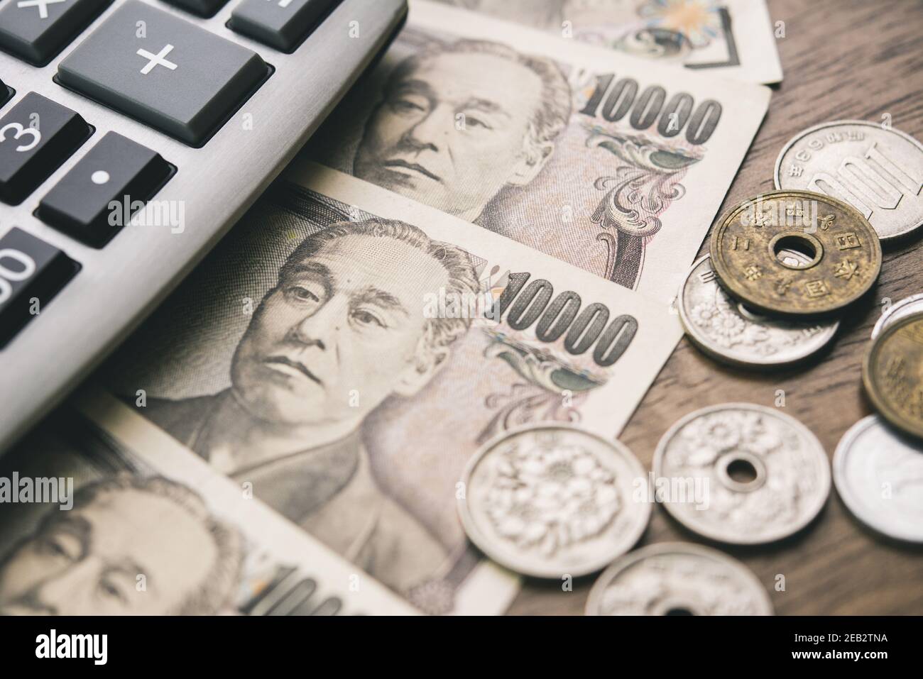 Cierre de billetes y monedas de yenes japoneses con calculadora sobre la mesa para los conceptos financieros y de inversión Foto de stock