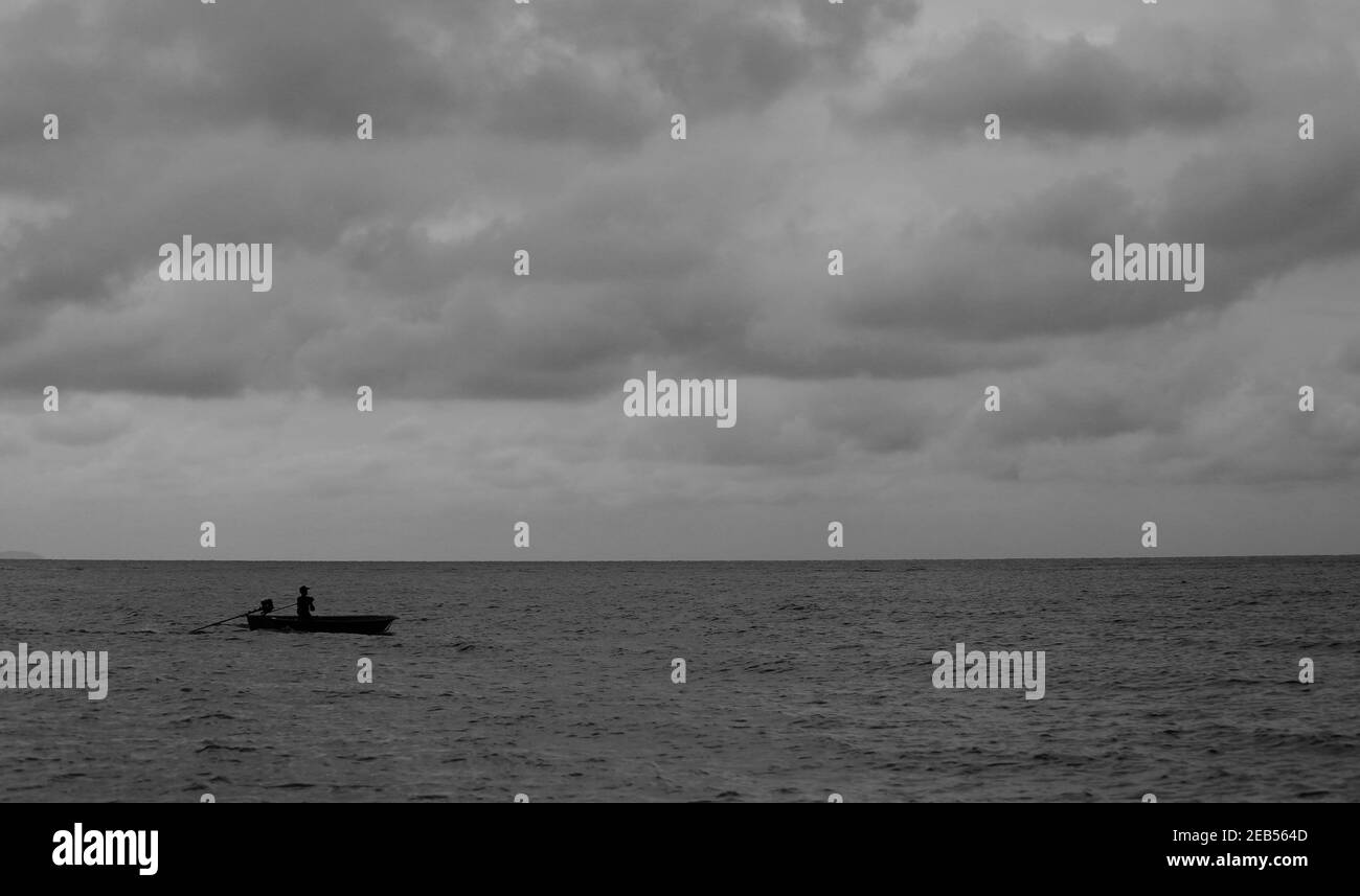 Un pequeño barco que corre en el mar y el cielo con nubes oscuras antes de la tormenta. Foto de stock