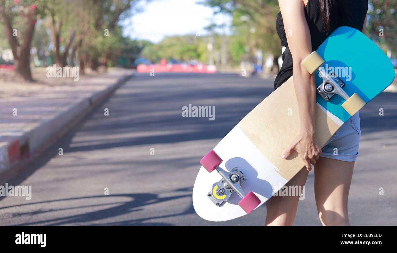 Primer plano sobre las mujeres jóvenes mano de la mano de patineta, surf  skate en el fondo del parque público. Libre relajarse skateboard concepto de  moda. Retrato de moda de la mujer