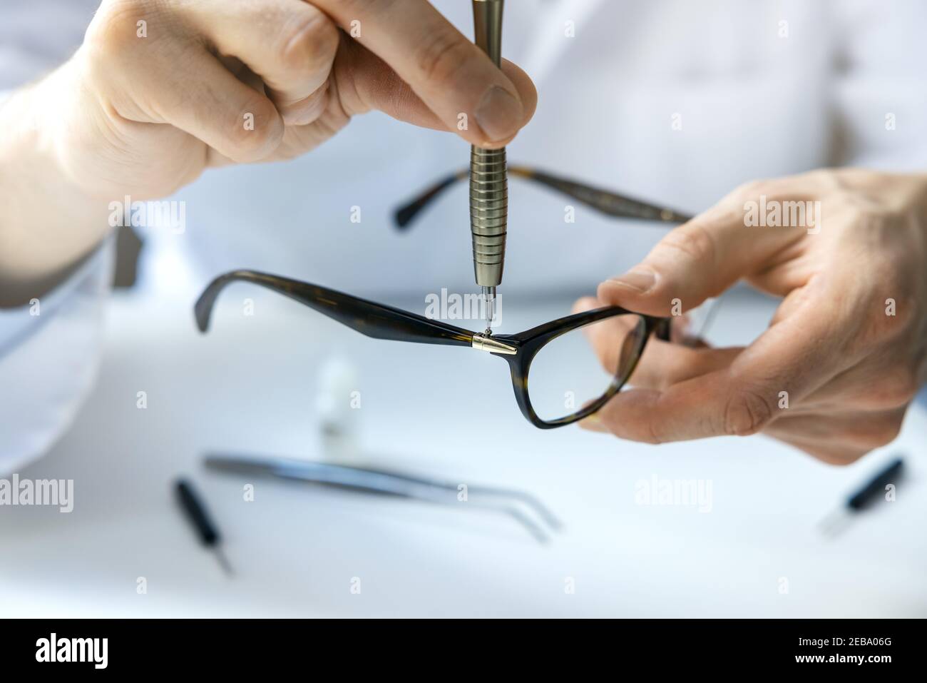 servicio de reparación de gafas - técnico óptico reparando marco de gafas con destornillador Foto de stock