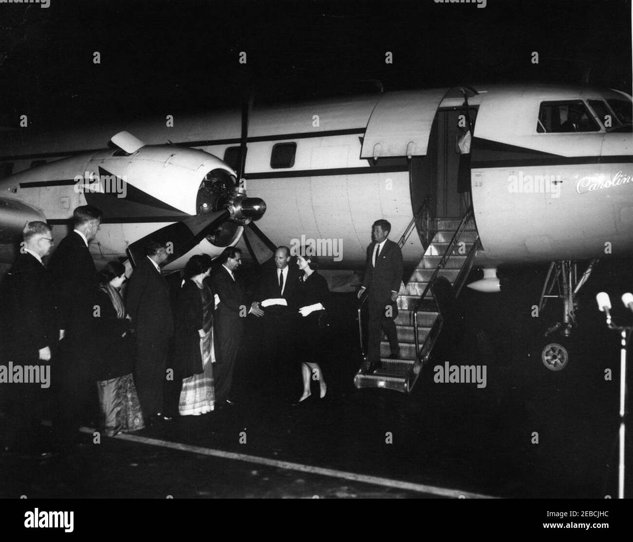 La Presidenta Kennedy saluda a la primera Dama Jacqueline Kennedy (JBK) en la base de la Fuerza Aérea Andrews al regresar de su viaje a la India y Pakistán, a las 7:25 PM. Un grupo saluda a la primera Dama Jacqueline Kennedy cuando regresa de su viaje a la India y Pakistán. L-R) Subsecretario de Estado para Asuntos del cercano Oriente y Asia Meridional Phillips Talbot; Embajador de los Estados Unidos en la India John Kenneth Galbraith; Shobha u201cForiu201d Nehru (esposa de Braj Kumar Nehru, Embajador de la India en los Estados Unidos); Embajador Nehru; Shereen Ahmed (esposa de Aziz Ahmed, Embajador de Pakistán en los Estados Unidos); A. Foto de stock