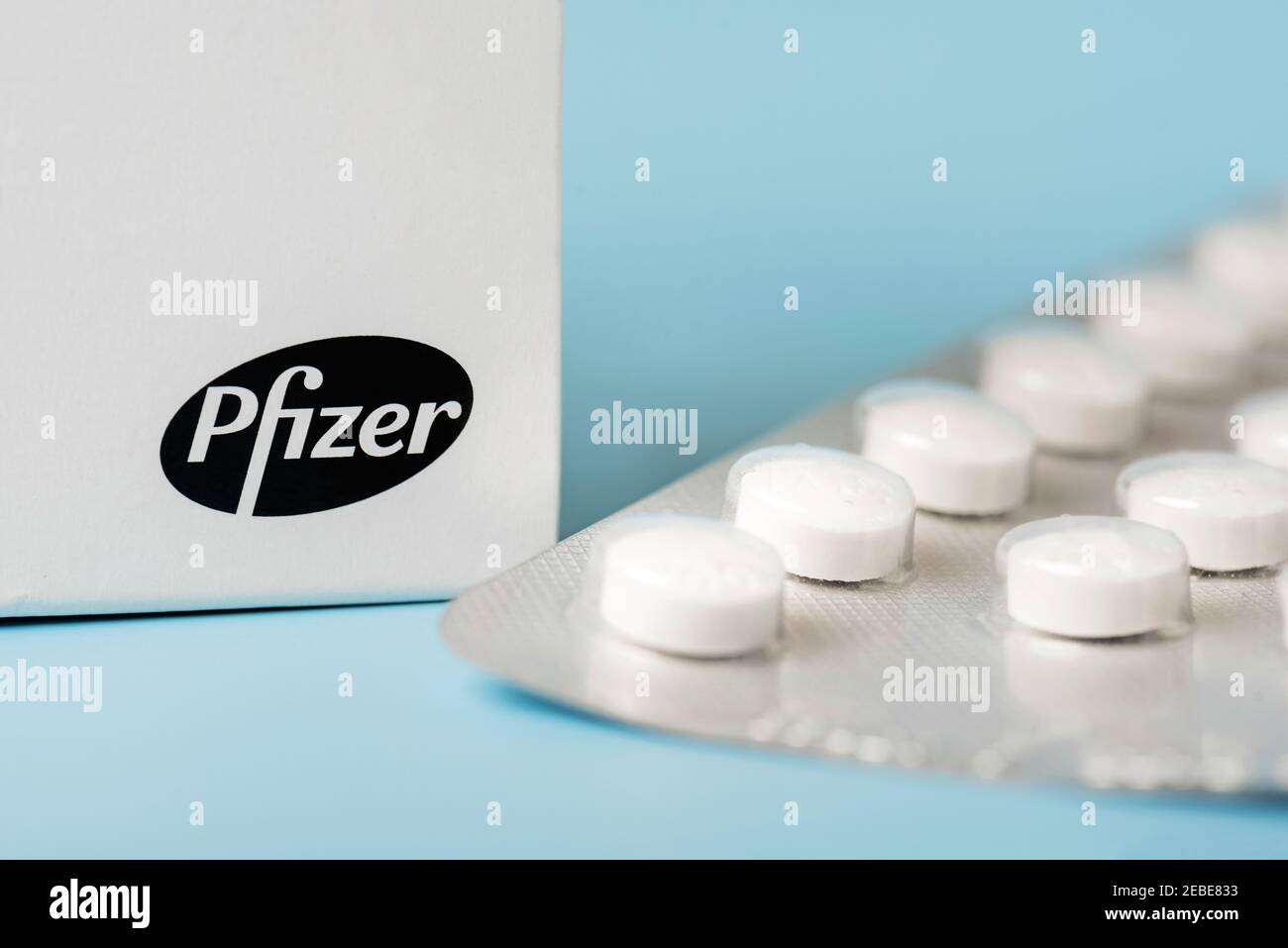 Caja y blíster de Pfizer con tabletas blancas en azul antecedentes Foto de stock