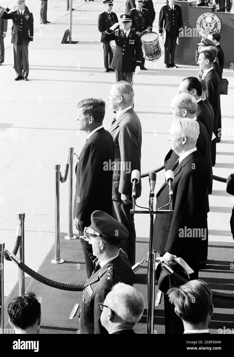 Ceremonias de llegada para Harold Macmillan, primer Ministro de Gran Bretaña, 4:50PM. Ceremonias de llegada en honor del primer Ministro de Gran Bretaña, Harold Macmillan. En la plataforma de revisión (L-R): El Presidente John F. Kennedy; el primer Ministro Macmillan; el Embajador de los Estados Unidos en Gran Bretaña, David K. E. Bruce; el Secretario de Estado, Dean Rusk; y el Embajador de Gran Bretaña, Sir David Ormsby-Gore (parcialmente oculto). De pie en grupo a la derecha del Embajador Ormsby-Gore (de frente a atrás): Secretario del Gabinete del PMu2019s, Sir Norman Brook (en su mayoría oculto); Subsecretario Adjunto de Foto de stock