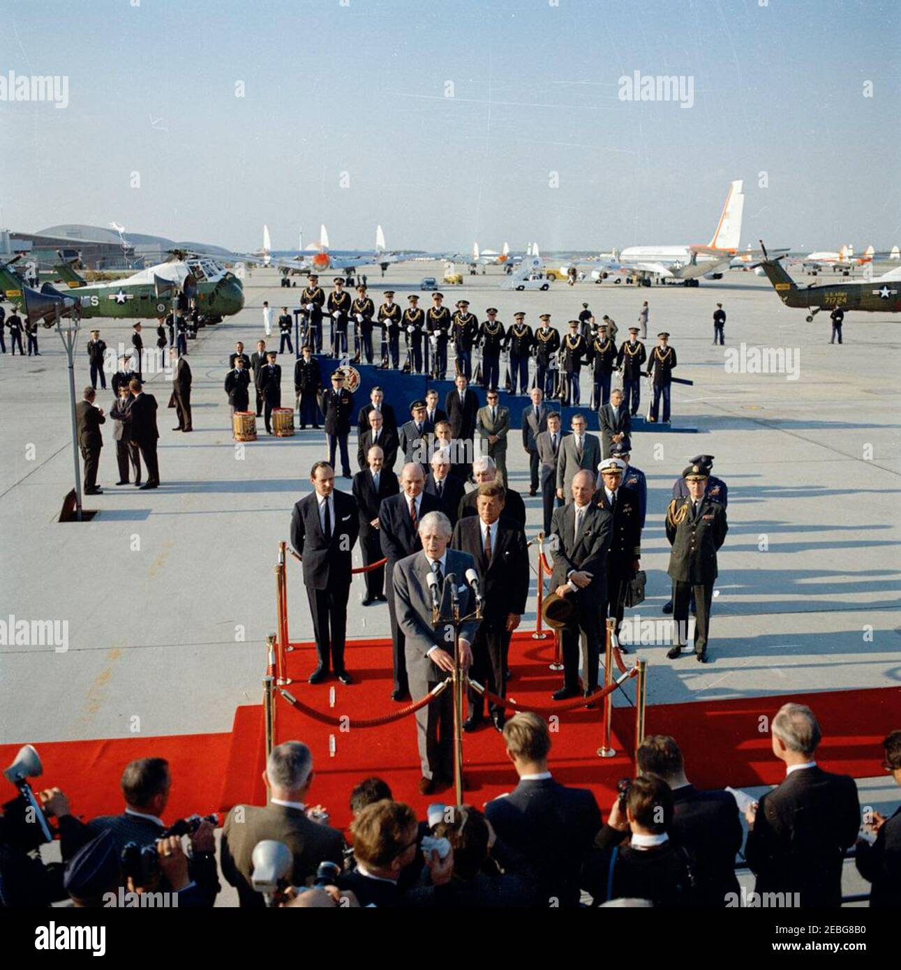 Ceremonias de llegada para Harold Macmillan, primer Ministro de Gran Bretaña, 4:50PM. El primer Ministro de Gran Bretaña, Harold Macmillan, pronuncia sus palabras en su honor durante las ceremonias de llegada. En la plataforma de revisión (L-R): Embajador de Gran Bretaña, Sir David Ormsby-Gore; Secretario de Estado, Dean Rusk; primer Ministro Macmillan (en micrófonos); Presidente John F. Kennedy; Embajador de los Estados Unidos en Gran Bretaña, David K. E. Bruce (parcialmente oculto tras el Presidente Kennedy); y Jefe de Protocolo, Angier Biddle Duke. También en la foto: Subsecretario de Estado para la AF Europea Foto de stock