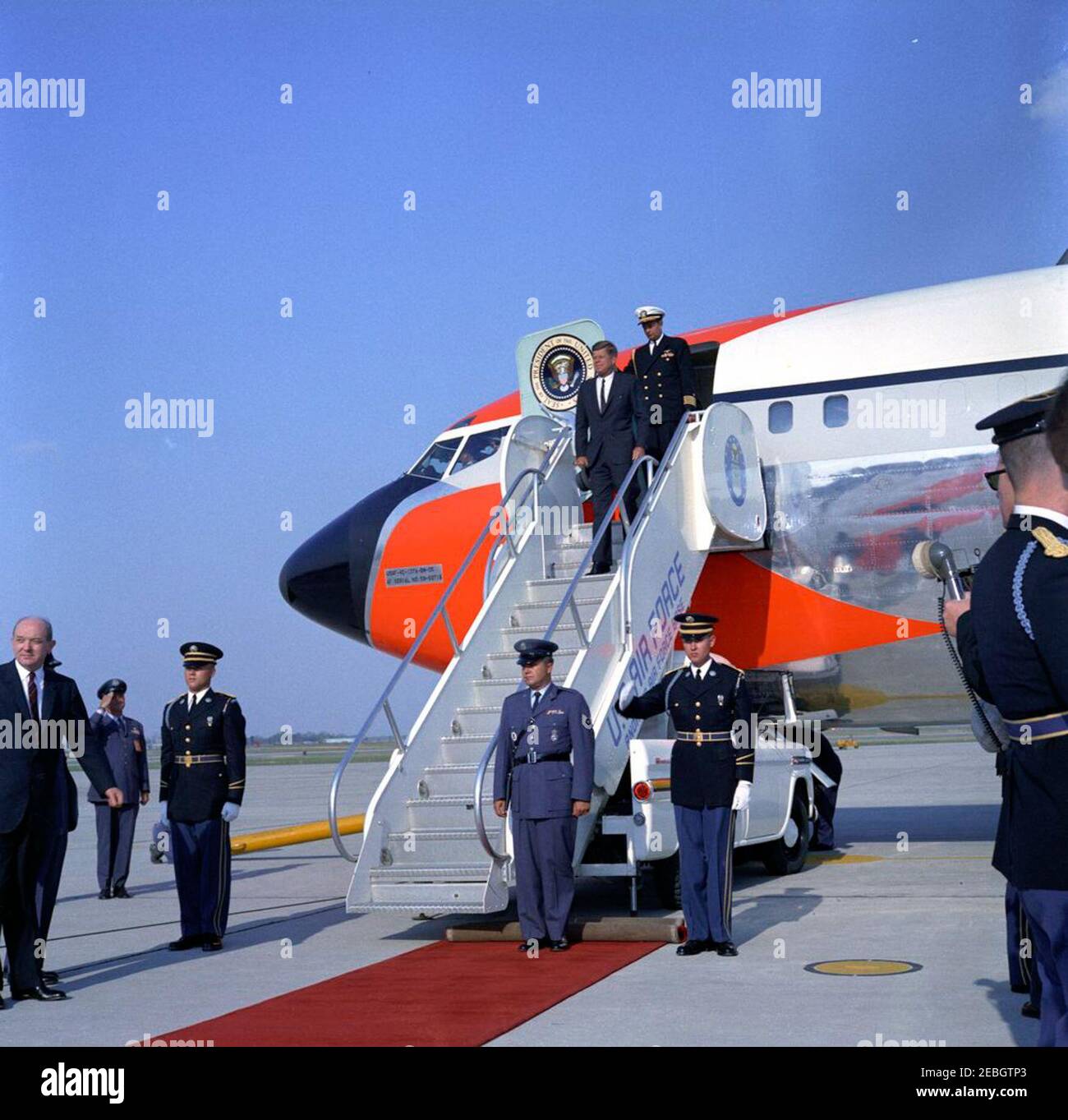 El Presidente Kennedy regresa a la base Andrews de la Fuerza Aérea desde las vacaciones de Semana Santa, 4:33 PM. El presidente John F. Kennedy (sombrero de retención) sale de la Fuerza Aérea uno a su llegada a la base Andrews de la Fuerza Aérea, Maryland, después de las vacaciones de Semana Santa en Palm Beach, Florida. También en la foto: Aide Naval al Presidente, Capitán Tazewell T. Shepard, Jr. (En la parte superior de las escaleras del avión, detrás del Presidente Kennedy), y Secretario de Estado, Dean Rusk (abajo a la izquierda, en el borde del marco). Foto de stock