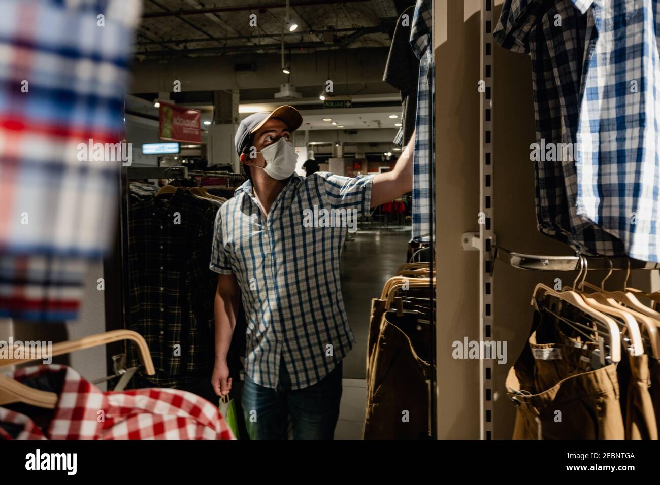 el hombre se reflejó en un espejo de la tienda de ropa, buscando comprar  ropa mientras llevaba una máscara médica. Falabella Buenos Aires Fotografía  de stock - Alamy
