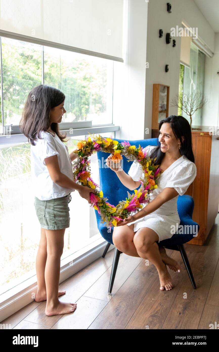 Hermosa hija le da un arreglo de flores en forma de corazón a su mamá Foto de stock