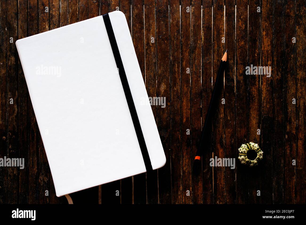 Libro blanco con portadas con lápiz negro sobre mesa rústica de madera  plano poner foto. Cuaderno cerrado con cubierta en blanco plano laico foto.  Bloc de notas sobre la mesa Fotografía de