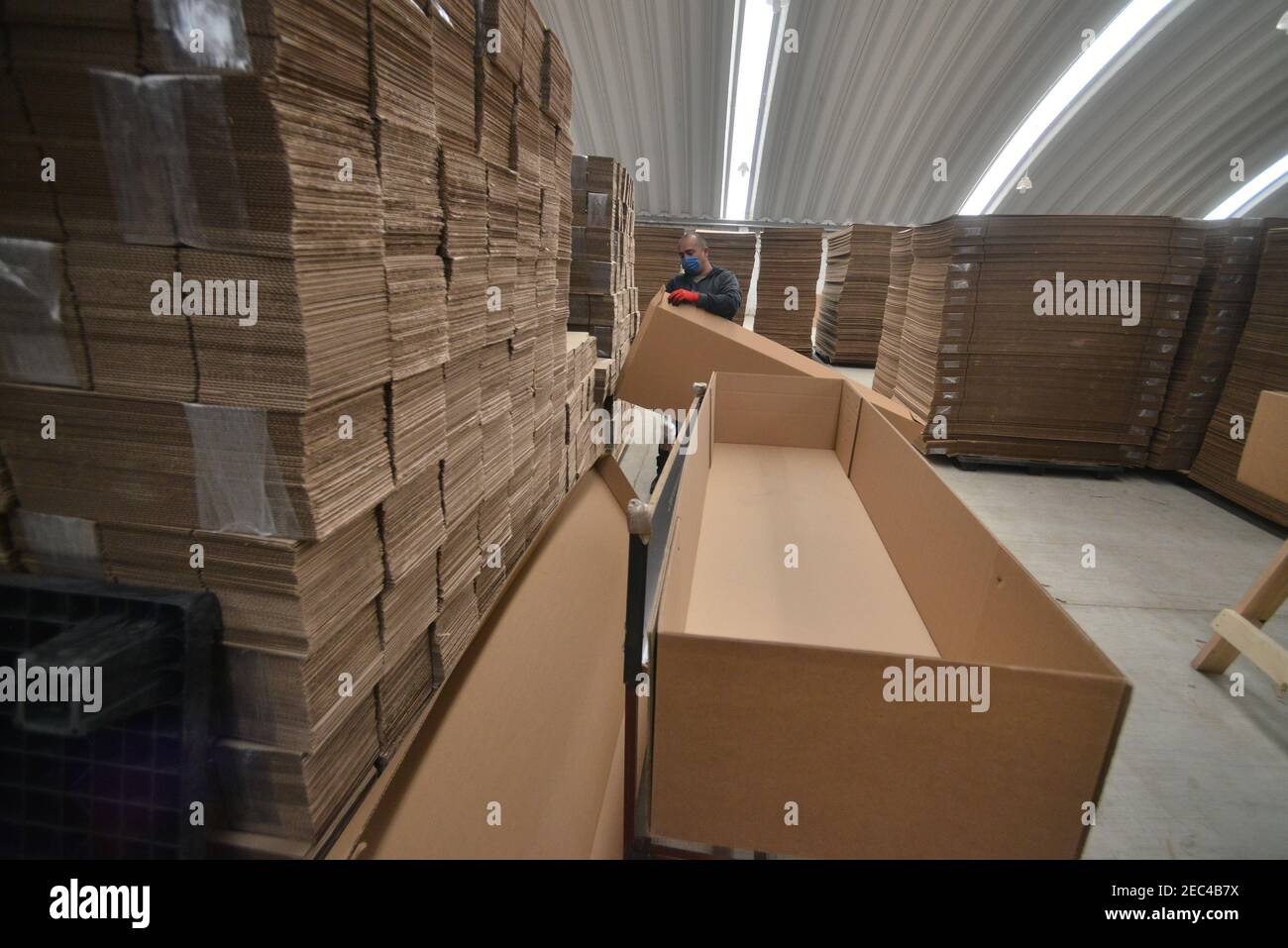 Toluca, México. 12 de febrero de 2021. Un trabajador de la fábrica de cajas  de cartón KJ, durante el montaje de un ataúd hecho de cartón. Debido al  aumento de las muertes