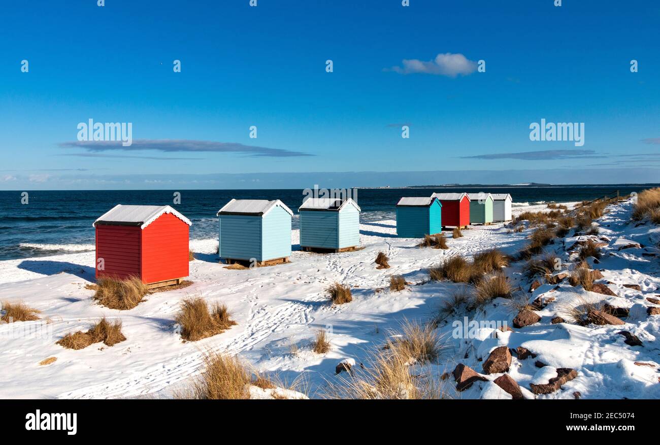 FINDHORN BAY MORAY FIRTH SCOTLAND SIETE COLORIDAS CABAÑAS O CHALETS EN UNA PLAYA CUBIERTA DE NIEVE EN INVIERNO Foto de stock