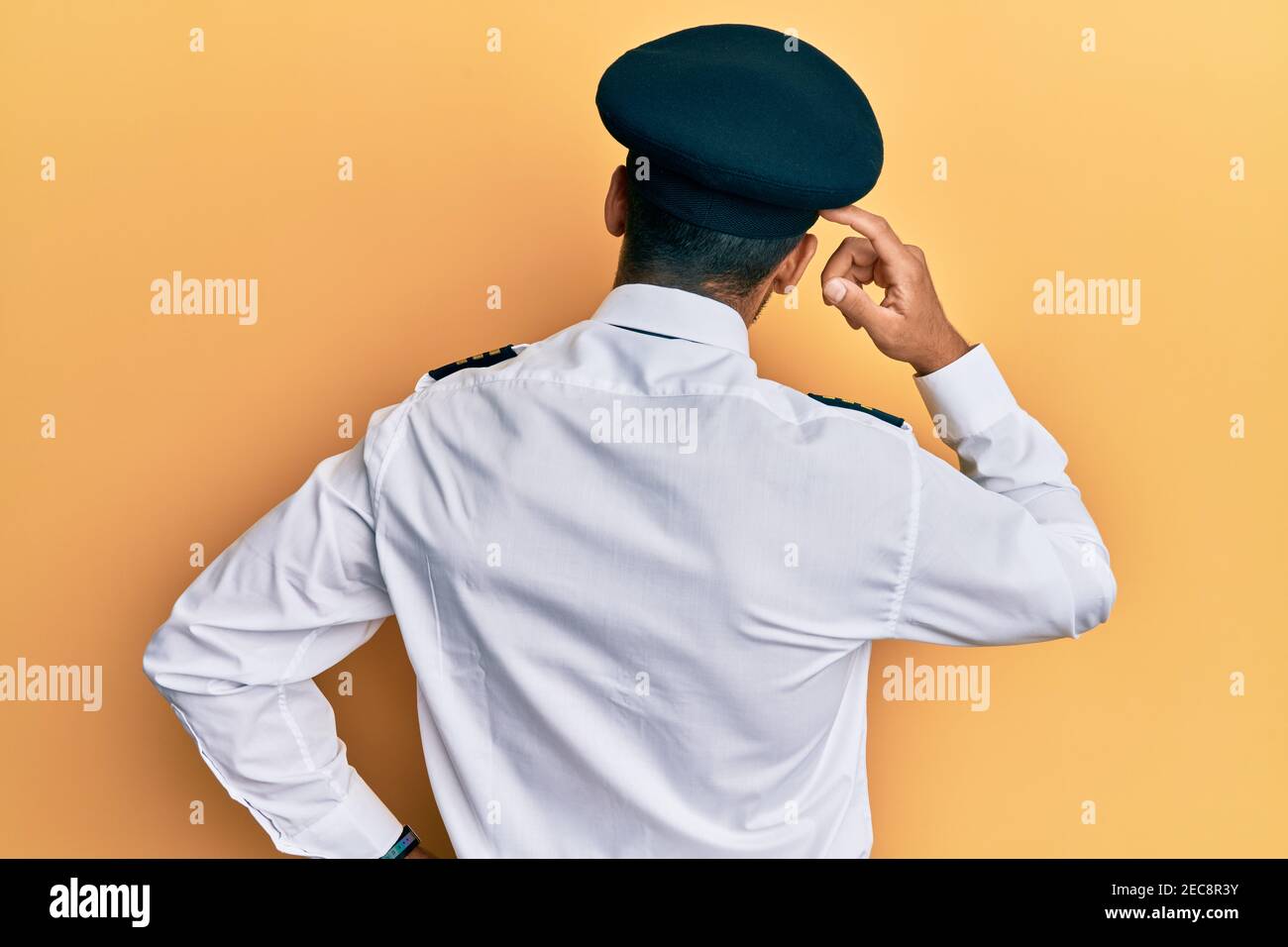 Un hombre hispano guapo con uniforme piloto de avión pensando en lo  contrario duda con la mano en la cabeza Fotografía de stock - Alamy