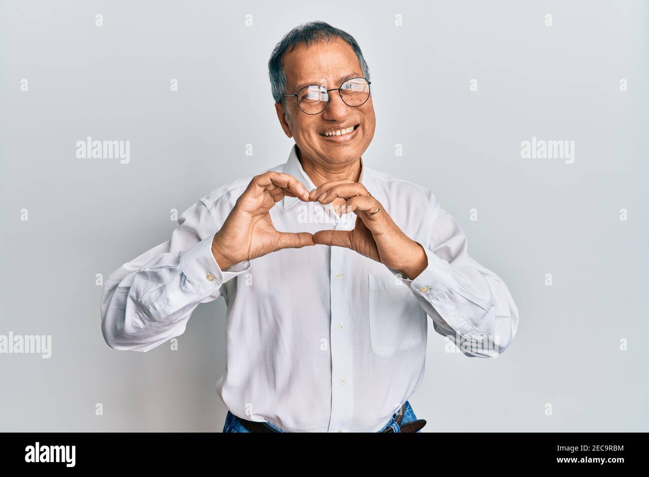 Edad media hombre de la india con ropa informal y gafas sonriendo en el  amor haciendo corazón símbolo forma con las manos. Concepto romántico  Fotografía de stock - Alamy
