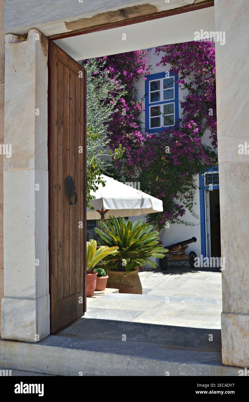 Casa neoclásica patio con una entrada de mármol blanco, puertas y ventanas  azules y blancas y una buganvilla rosa trepadora en Hydra Grecia Fotografía  de stock - Alamy