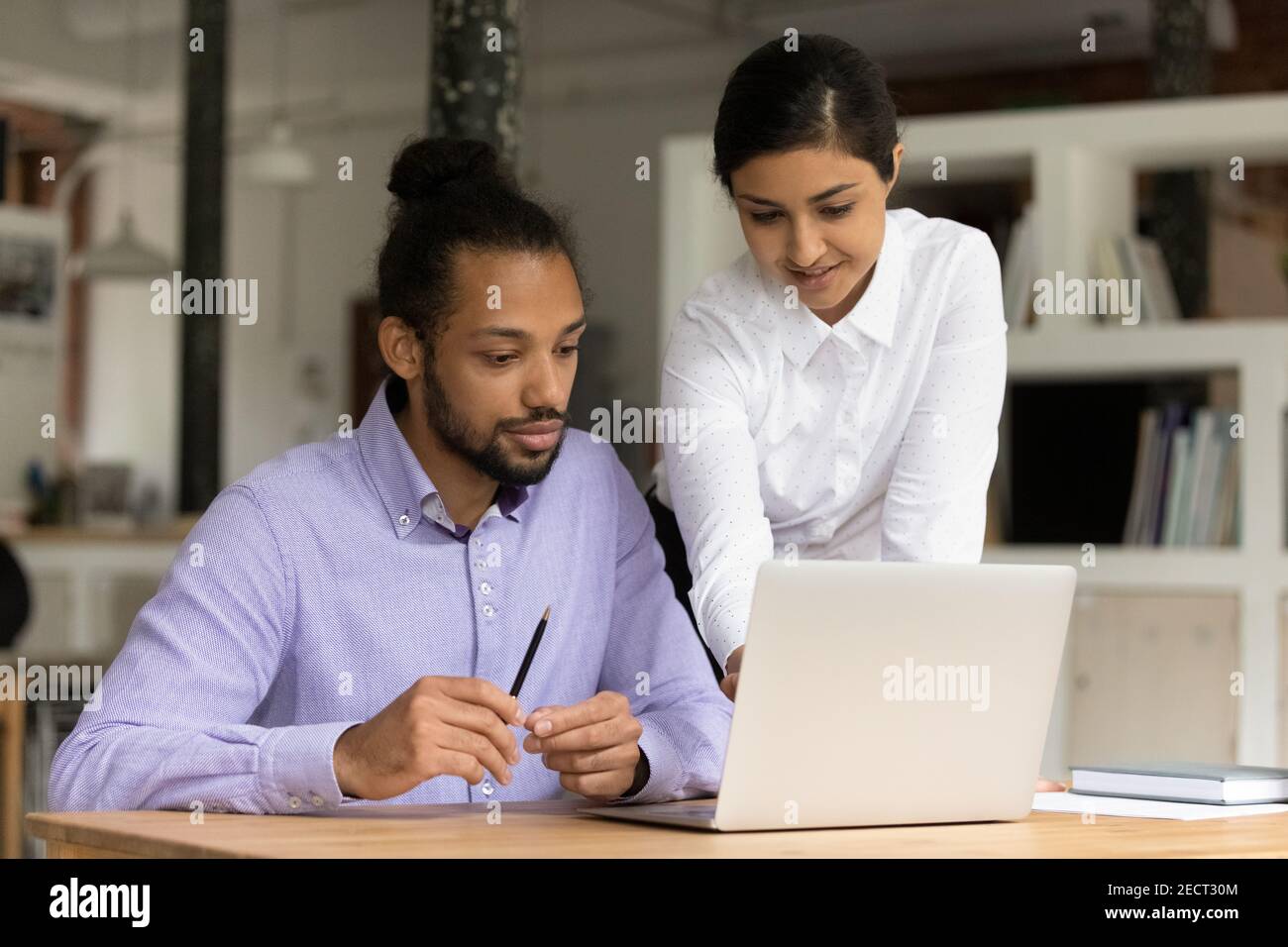 Los colegas multiétnicos trabajan juntos en el portátil de la oficina Foto de stock