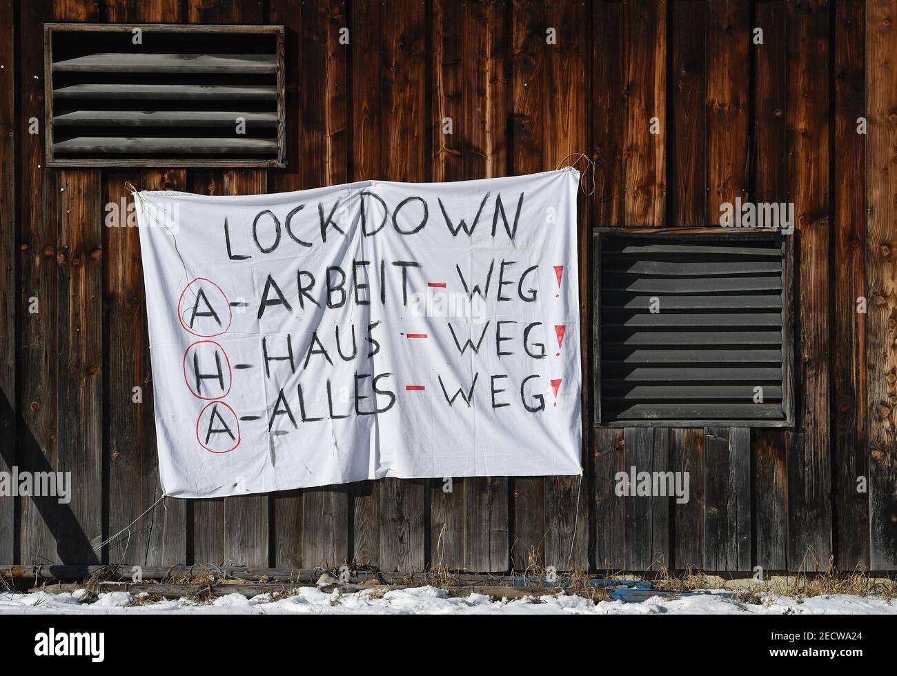 Neuhaus, Alemania. 14 de febrero de 2021. Un banner con el texto "Lockdown AHA Work-away, house-away, everything-away" cuelga de una pila de madera. Crédito: Angelika warmuth/dpa/Alamy Live News Foto de stock