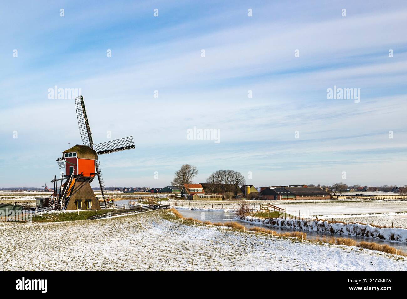 Icónica escena holandesa de invierno, patinaje sobre hielo en un paisaje de polder con el Rode Molen, un histórico molino de correos en Oud Ade, Holanda del Sur, Holanda. Foto de stock
