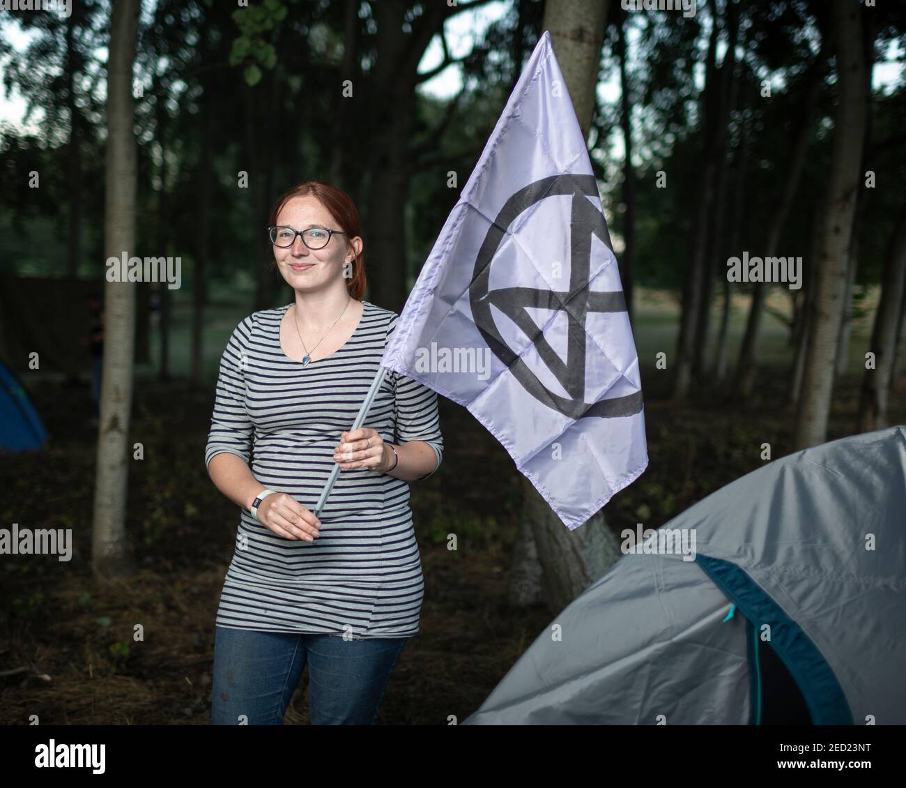 Una activista de extinción Rebellion se encuentra fuera de su tienda de campaña con una bandera en un campamento en Brockwell Park, Londres, 31 de agosto de 2020 Foto de stock