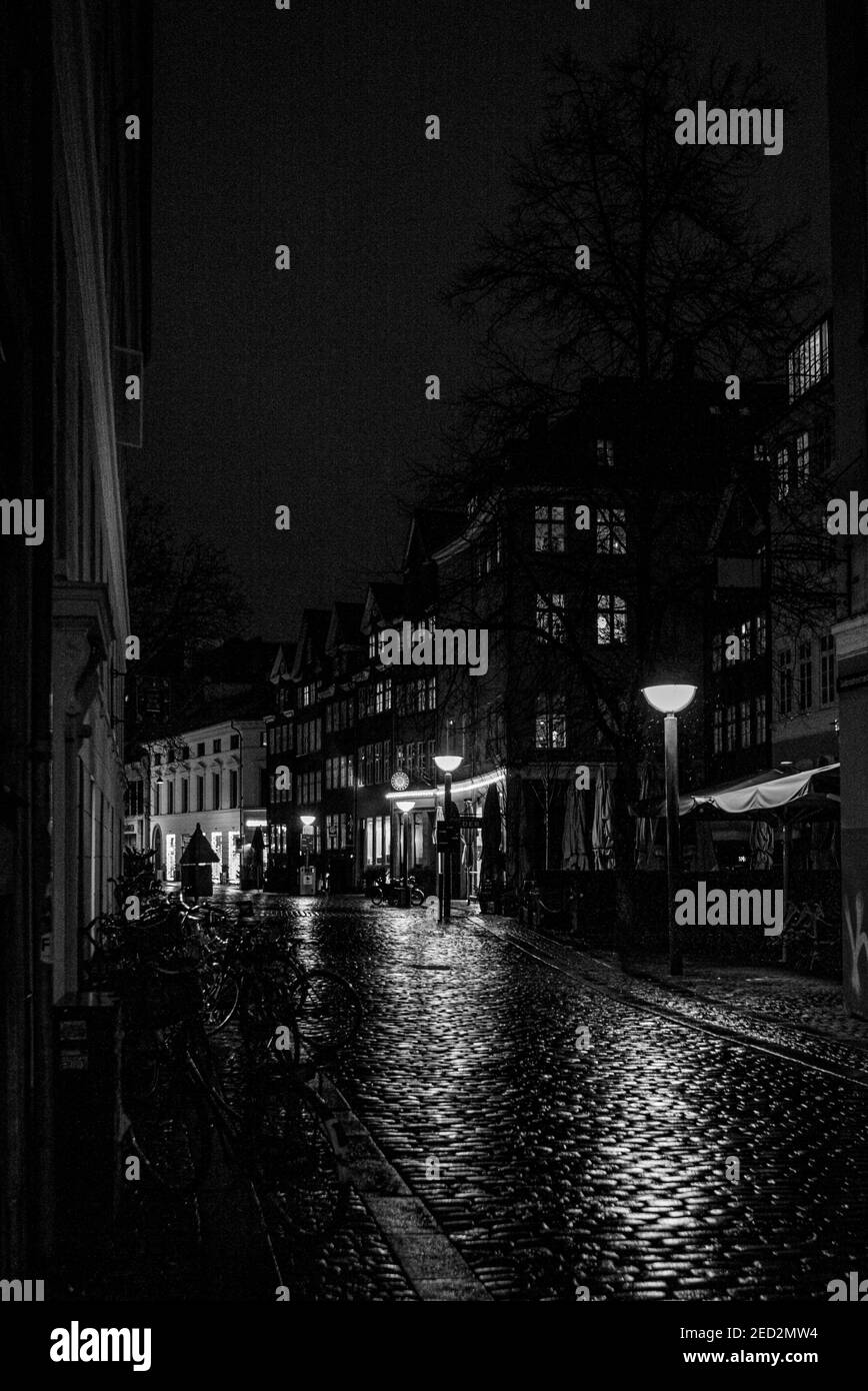 Luces que se reflejan en la calle pavimentada del centro de Copenhague Foto de stock