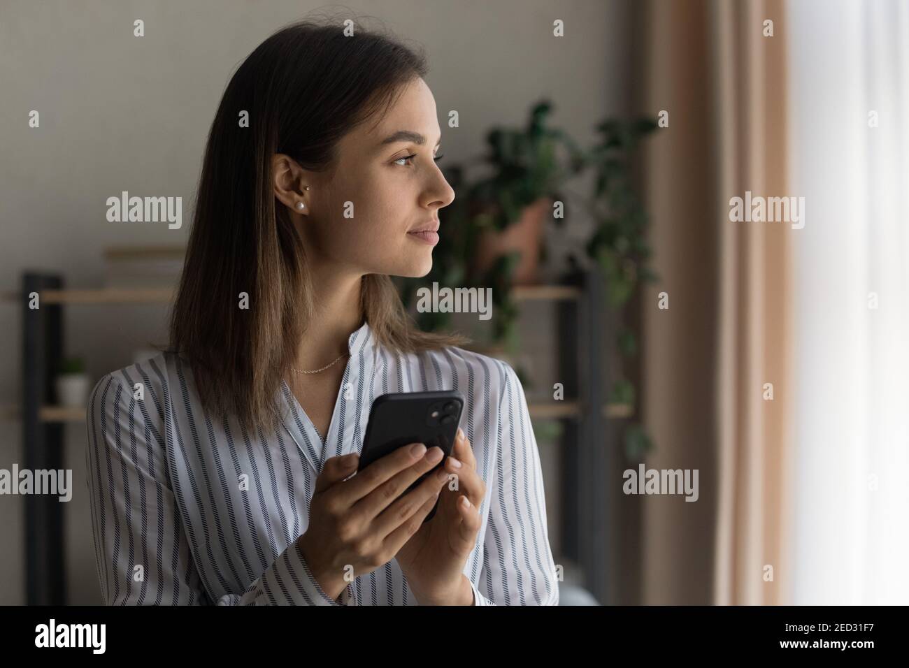 Chica joven pensativa mantener la celda mira a un lado sueño relajante Foto de stock