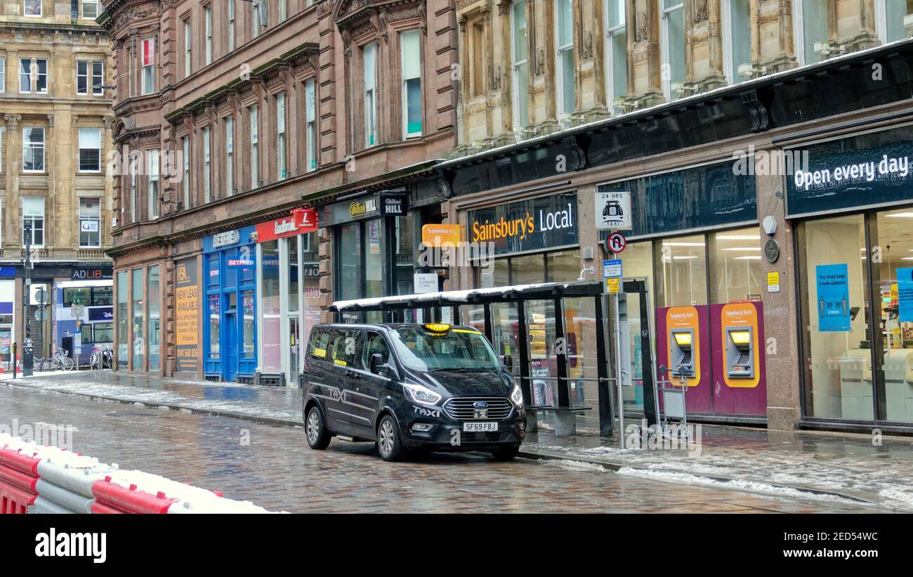 Glasgow, Escocia, Reino Unido. 14 de febrero de 2021, Reino Unido tiempo: Solo un taxi acudió a trabajar fuera de la estación central, ya que los conductores se han dado por vencidos, las temperaturas frías cedieron al trineos que vieron la nieve lentamente disiparse para desconcharse en la ciudad, ya que el día de San Valentín vio calles vacías con las únicas multitudes en el parque kelvingrove haciendo ejercicio y caminando perros. Crédito: Gerard Ferry/Alamy Live News Foto de stock