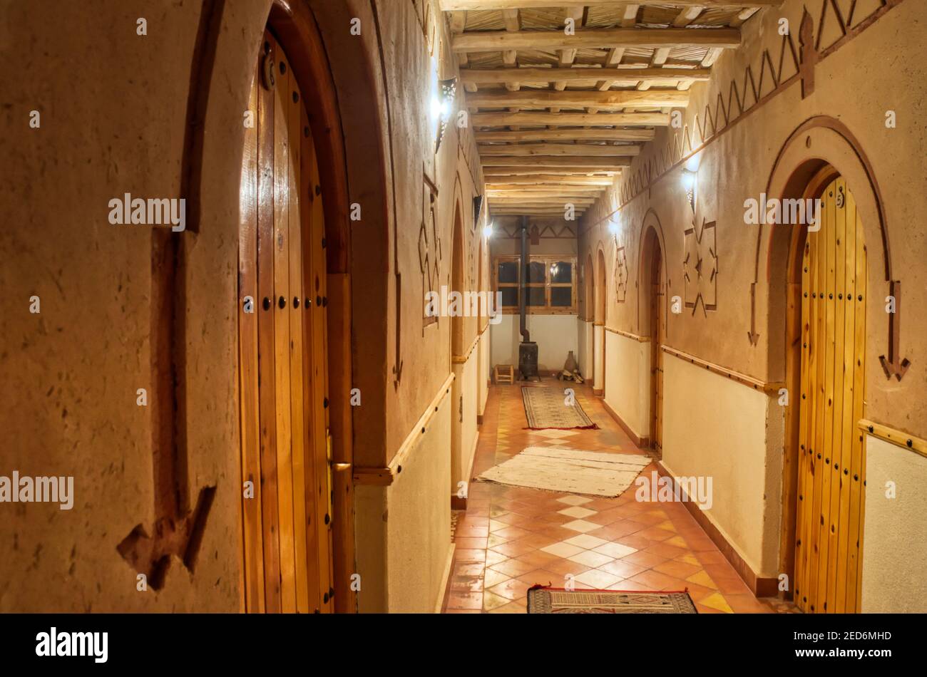 Pasillo del hotel con paredes de arcilla y puertas de madera Foto de stock