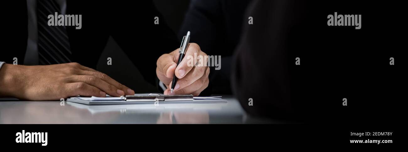 Empresario firma contrato en la mesa en sala oscura, fondo de banner panorámico con espacio de copia Foto de stock