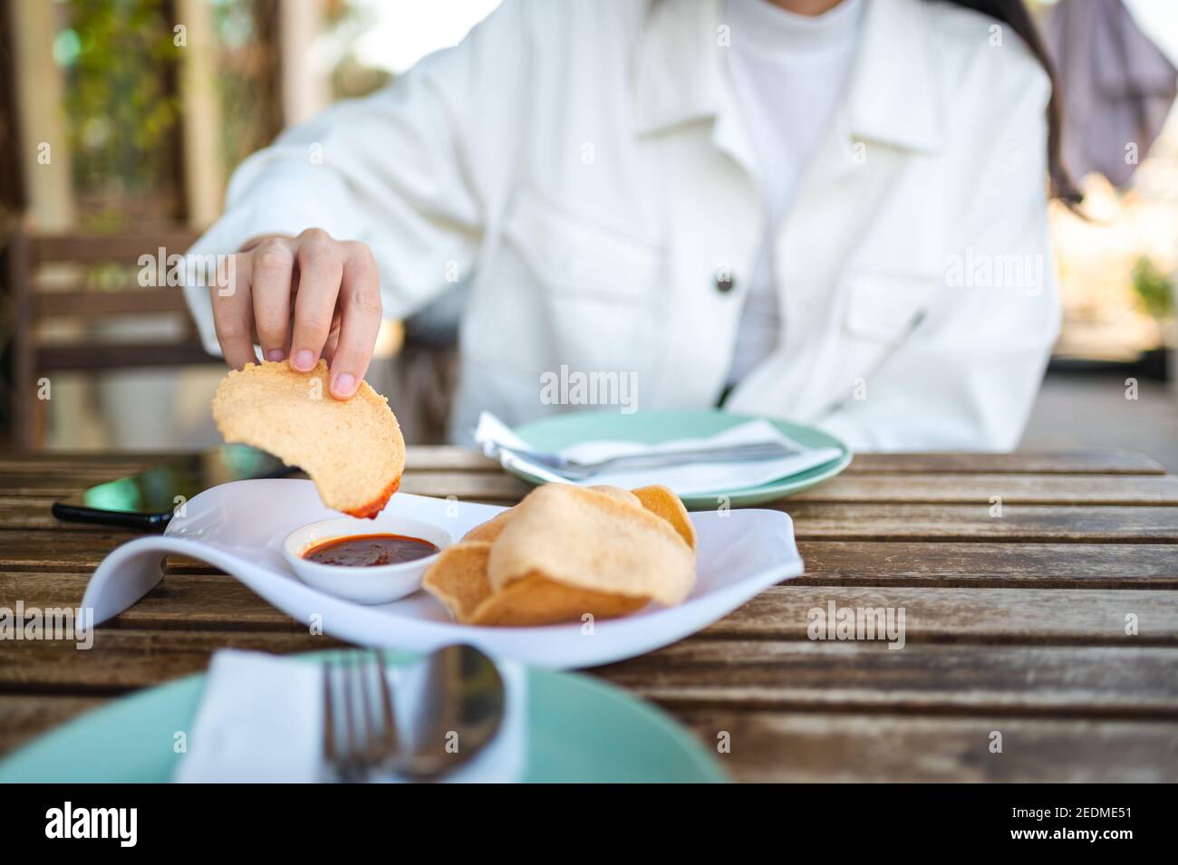 Mujer que tiene un aperitivo de galletas de gambas tailandesas antes de comer en el Restaurante de comida tailandesa Foto de stock