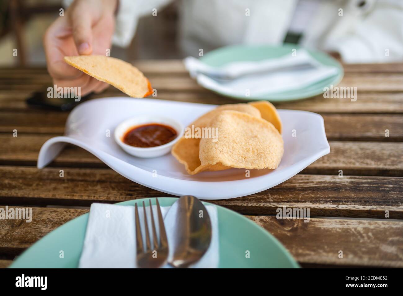 Mujer que tiene un aperitivo de galletas de gambas tailandesas antes de comer en el Restaurante de comida tailandesa Foto de stock