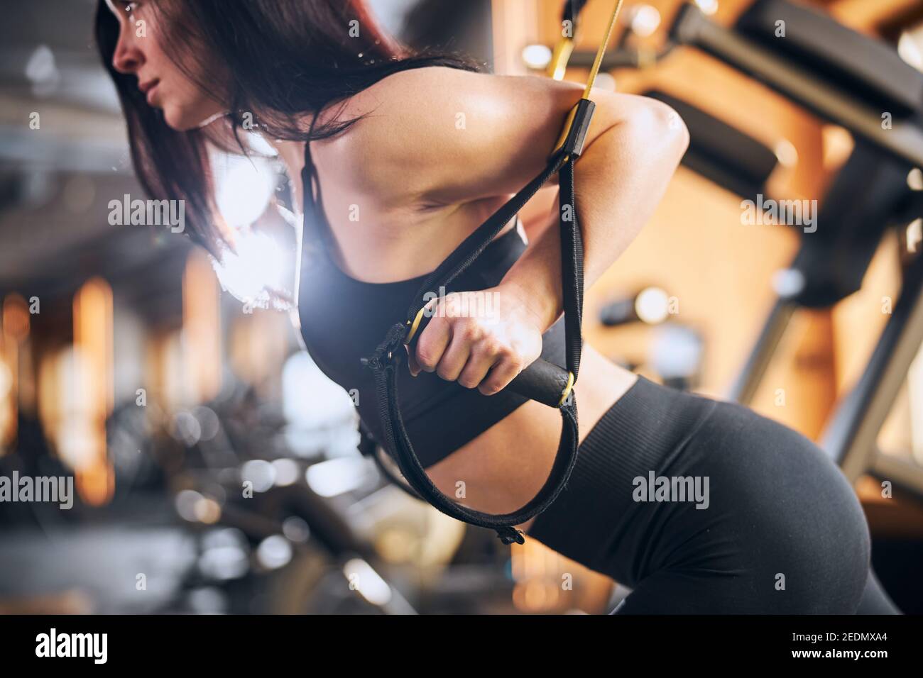 Mujer joven atlética haciendo ejercicio con correas de fitness Foto de stock