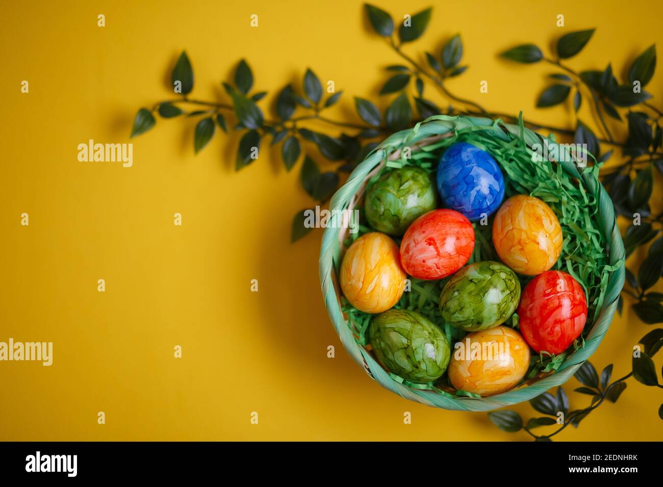 Tarjeta de Pascua. Composición plana con huevos de pascua en una cesta sobre fondo amarillo. Vista superior Foto de stock