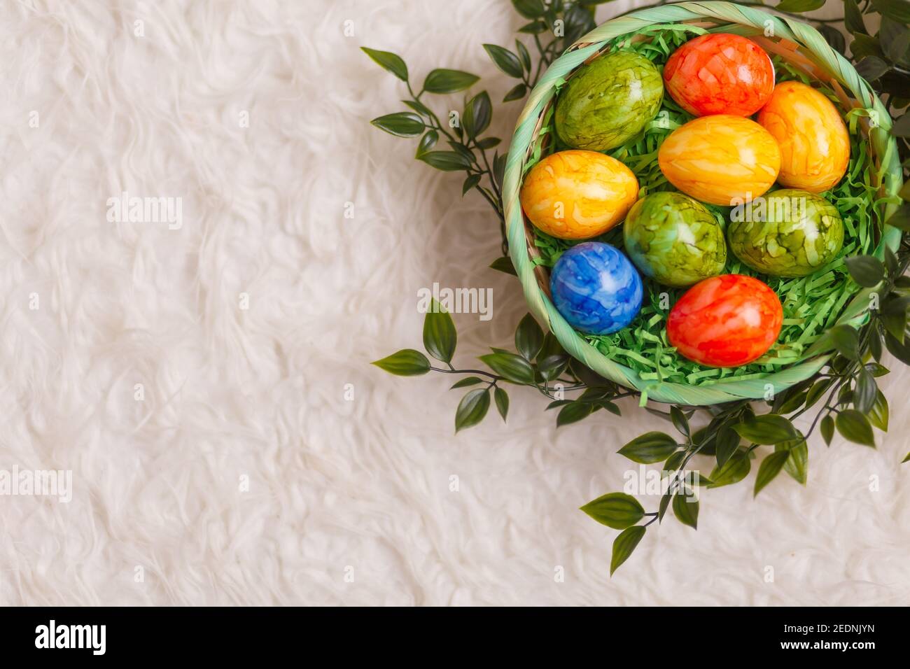 Tarjeta de Pascua. Composición plana con huevos de pascua en una cesta sobre fondo blanco. Vista superior Foto de stock