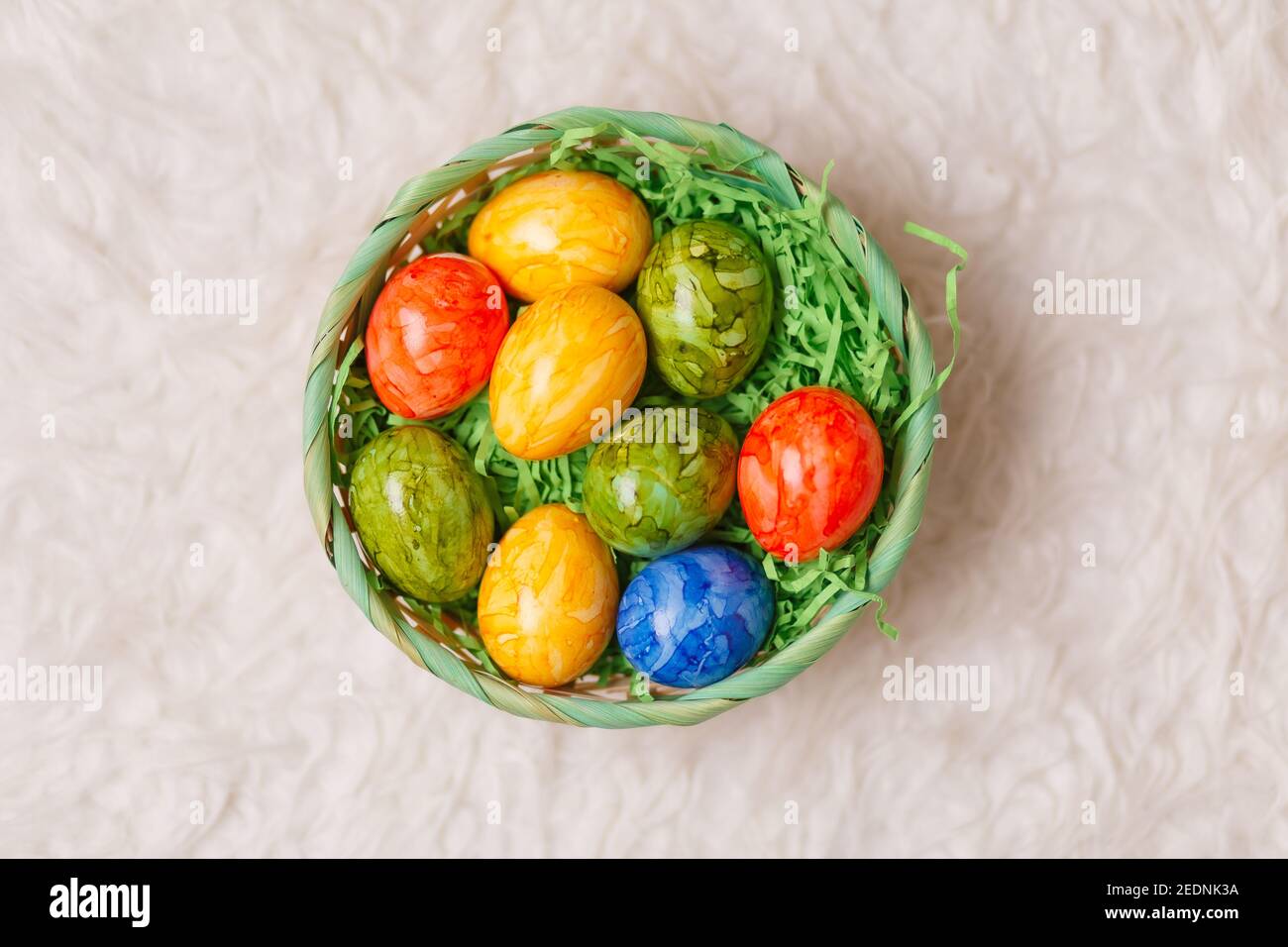 Tarjeta de Pascua. Composición plana con huevos de pascua en una cesta sobre fondo blanco. Vista superior Foto de stock