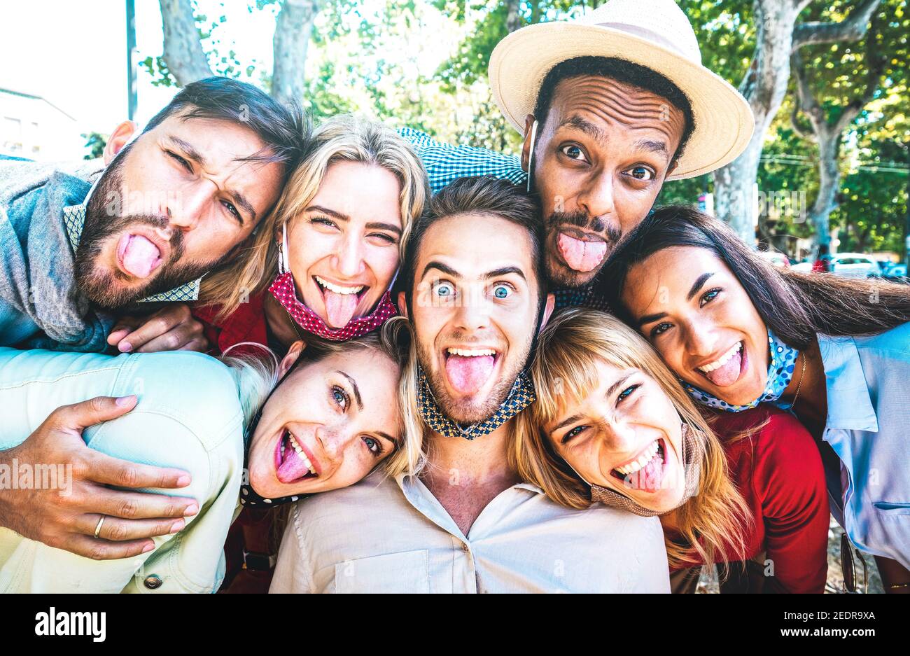 Amigos multiculturales tomando selfie loco que se pegan fuera de la lengua durante Covid 19 tercera ola - Nuevo concepto de estilo de vida normal Foto de stock