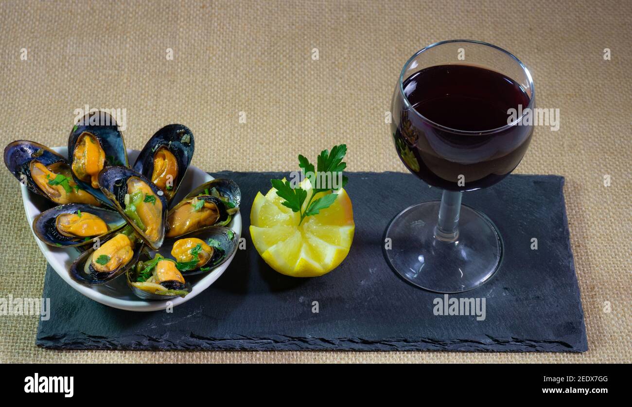 plato de mejillones con copa de vino tinto Foto de stock