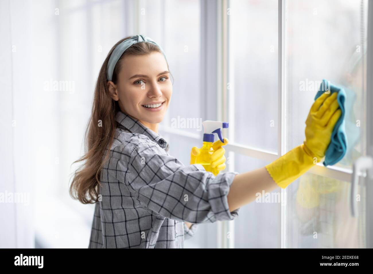 El joven está usando un trapo y una escobilla de goma mientras limpia las  ventanas. limpiador de ventanas profesional