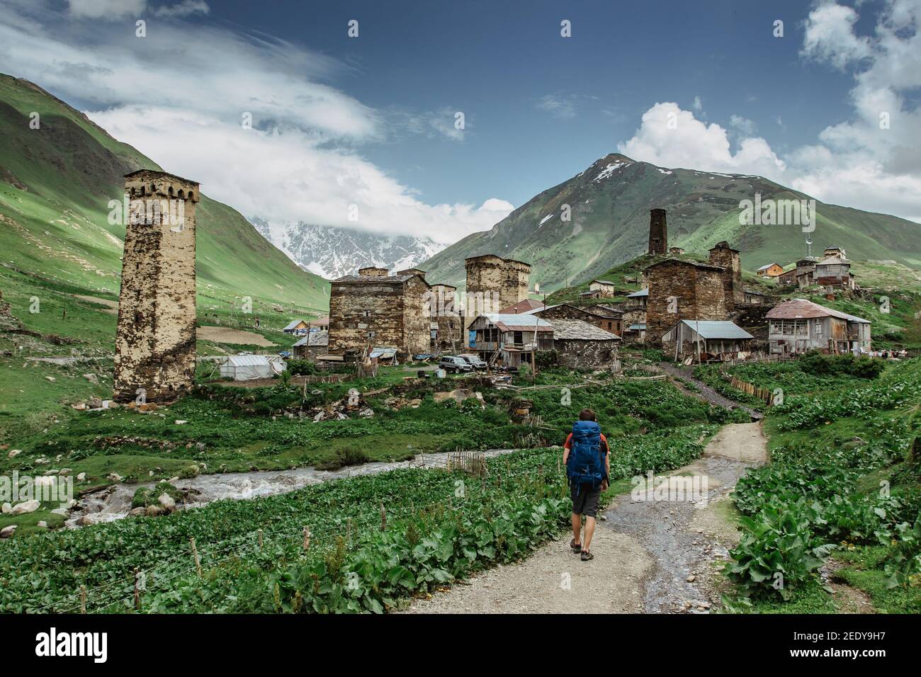Feliz hombre viajero en Ushguli, sitio de la UNESCO, Georgia.Backpacker explorar el Gran Cáucaso Casas rurales de piedra, vida de pueblo, pura salvaje Foto de stock