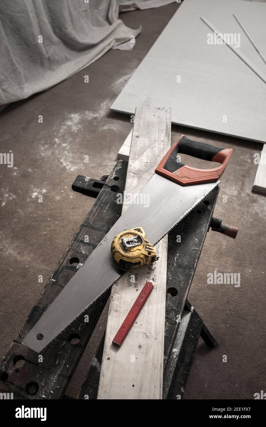 Sierra de mano, cinta métrica y lápiz en un trozo de madera cortada. Foto de stock