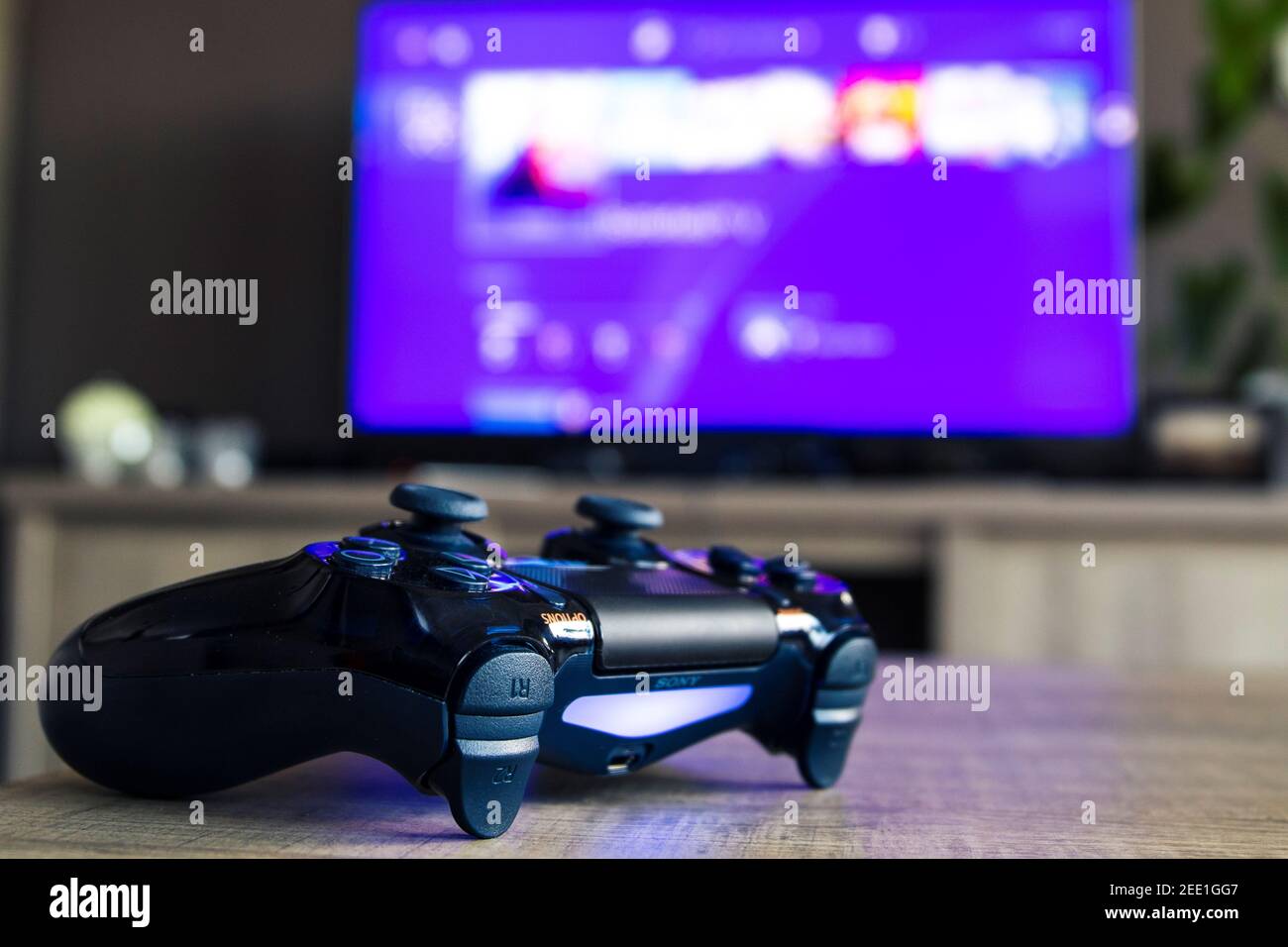 Un primer retrato de un dispositivo de videojuegos playstation 4 de sony  frente a un televisor con el menú de inicio de playstation. The PS4 cont  Fotografía de stock - Alamy