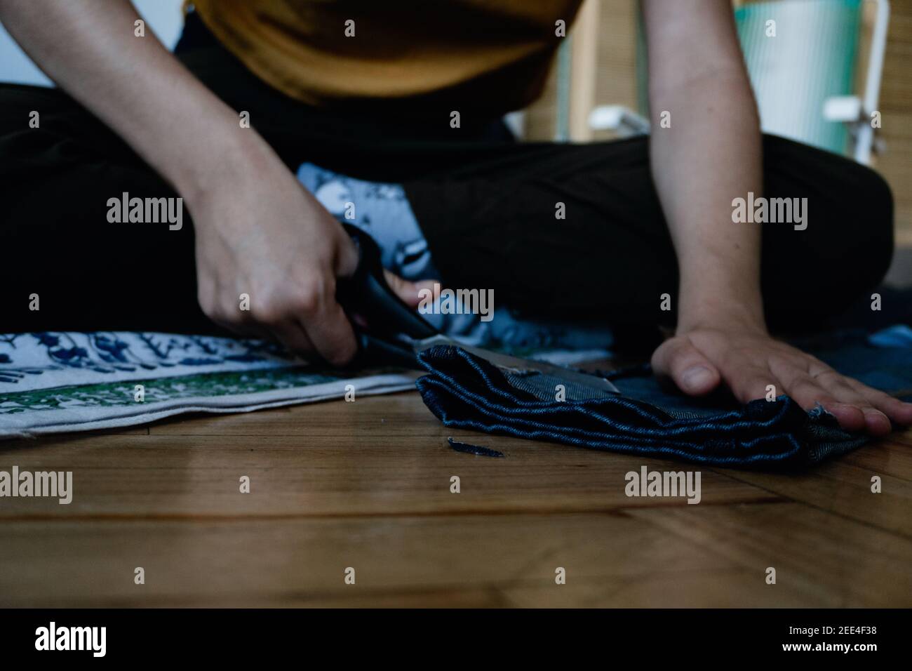 mujer que mendaba pantalones a mano con un par de tijeras, espíritu empresarial, trabajador explotado Foto de stock