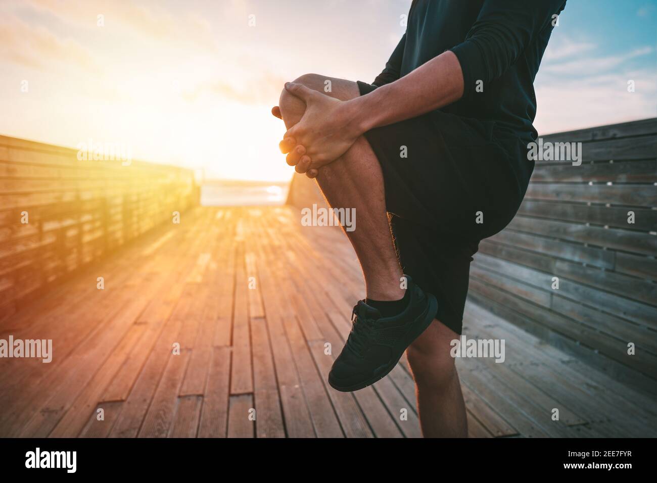Hombre joven sano calentando y estirando las piernas antes del entrenamiento al aire libre Foto de stock