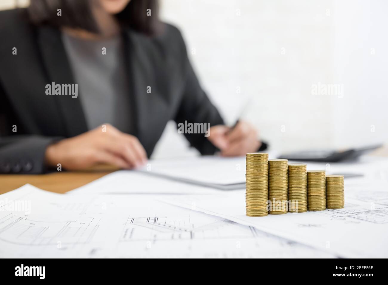 Empresaria revisando el documento con dinero y planos sobre la mesa - conceptos de inversión inmobiliaria y inmobiliaria Foto de stock