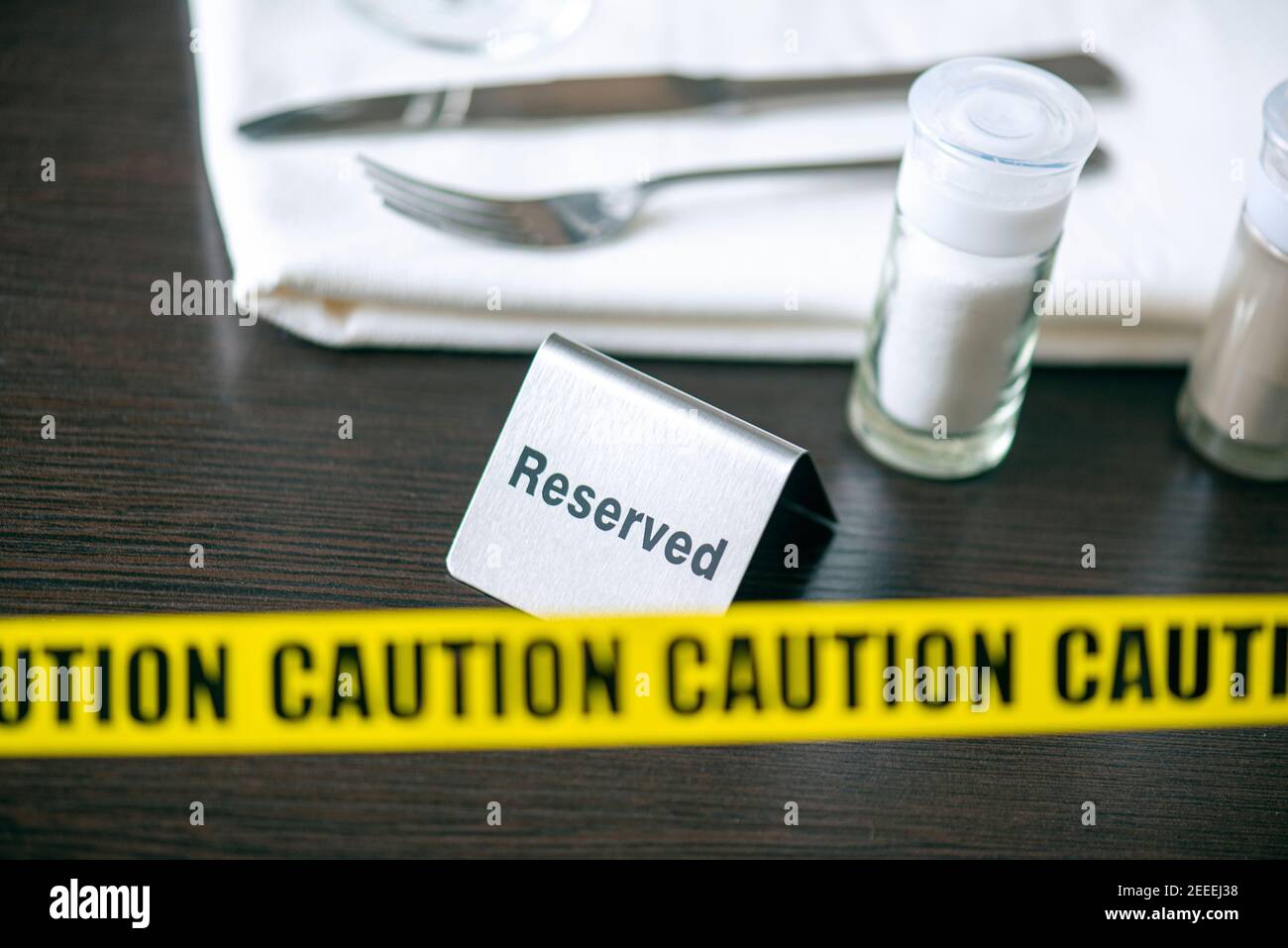 Precaución - cinta amarilla sobre la mesa en el café o restaurante y letrero reservado. Distanciamiento social Foto de stock