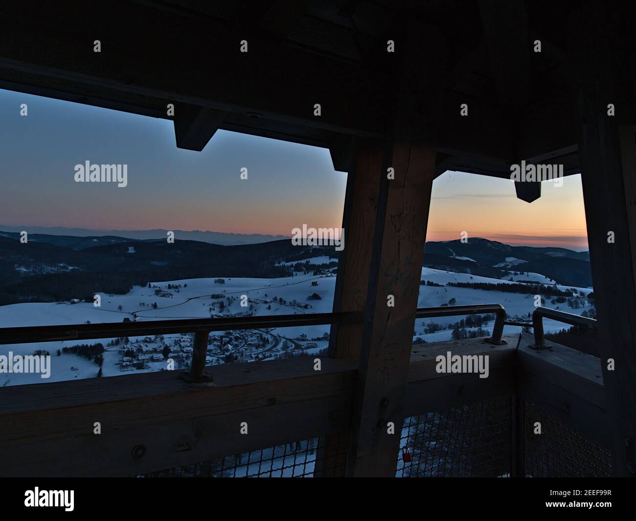 Espectacular vista de la puesta de sol sobre la Selva Negra con los Alpes en el horizonte desde la cima de la torre de observación Eugen-Keidel-Turm con prismáticos en invierno. Foto de stock