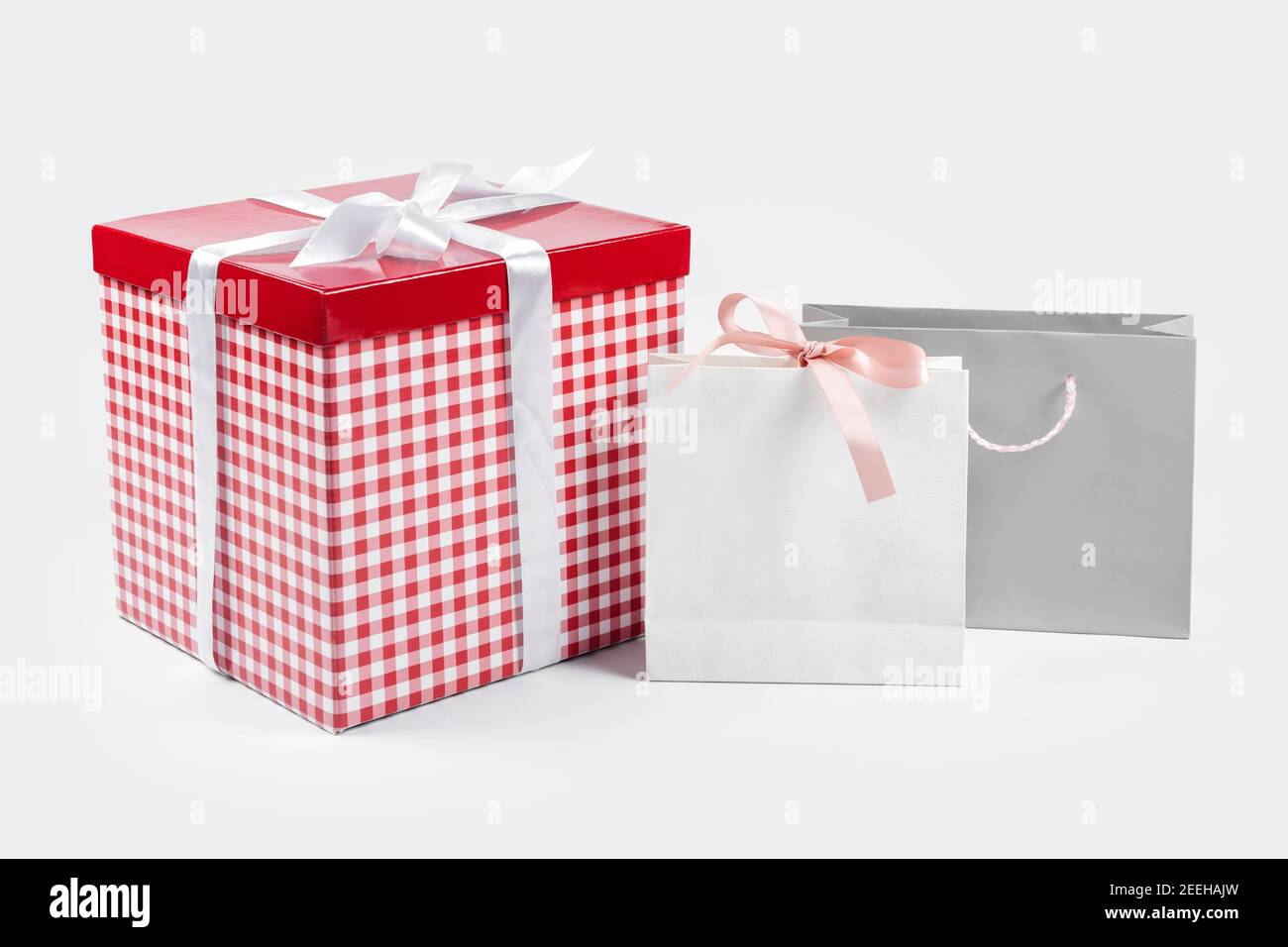 Cajas de regalo, sorpresa para las vacaciones. Concepto de regalo, compra y  venta. Caja de regalo roja con lazo de seda blanca en la parte superior y  bolsas de papel en la