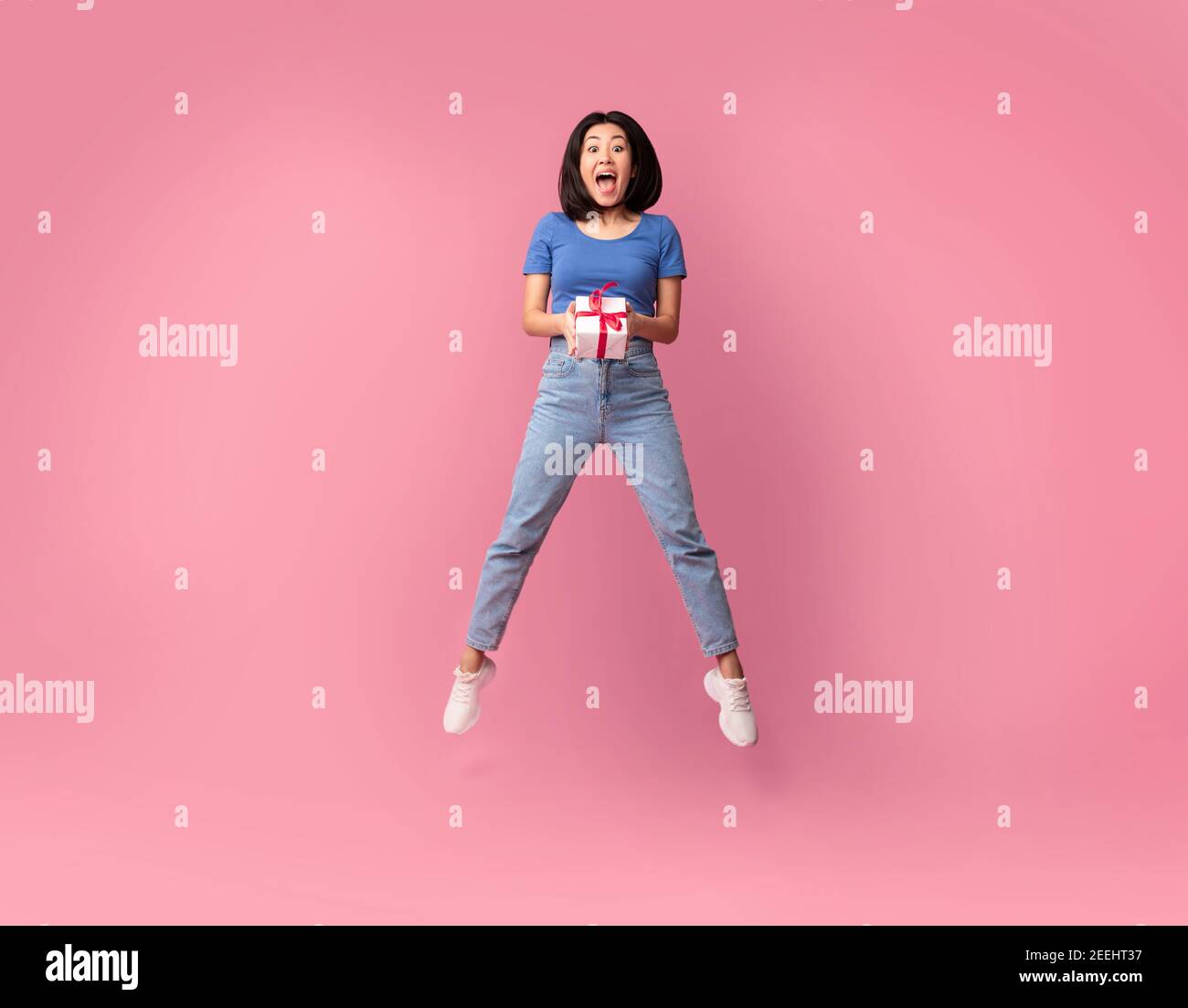 Saltando emocionada dama asiática sosteniendo la caja actual Foto de stock