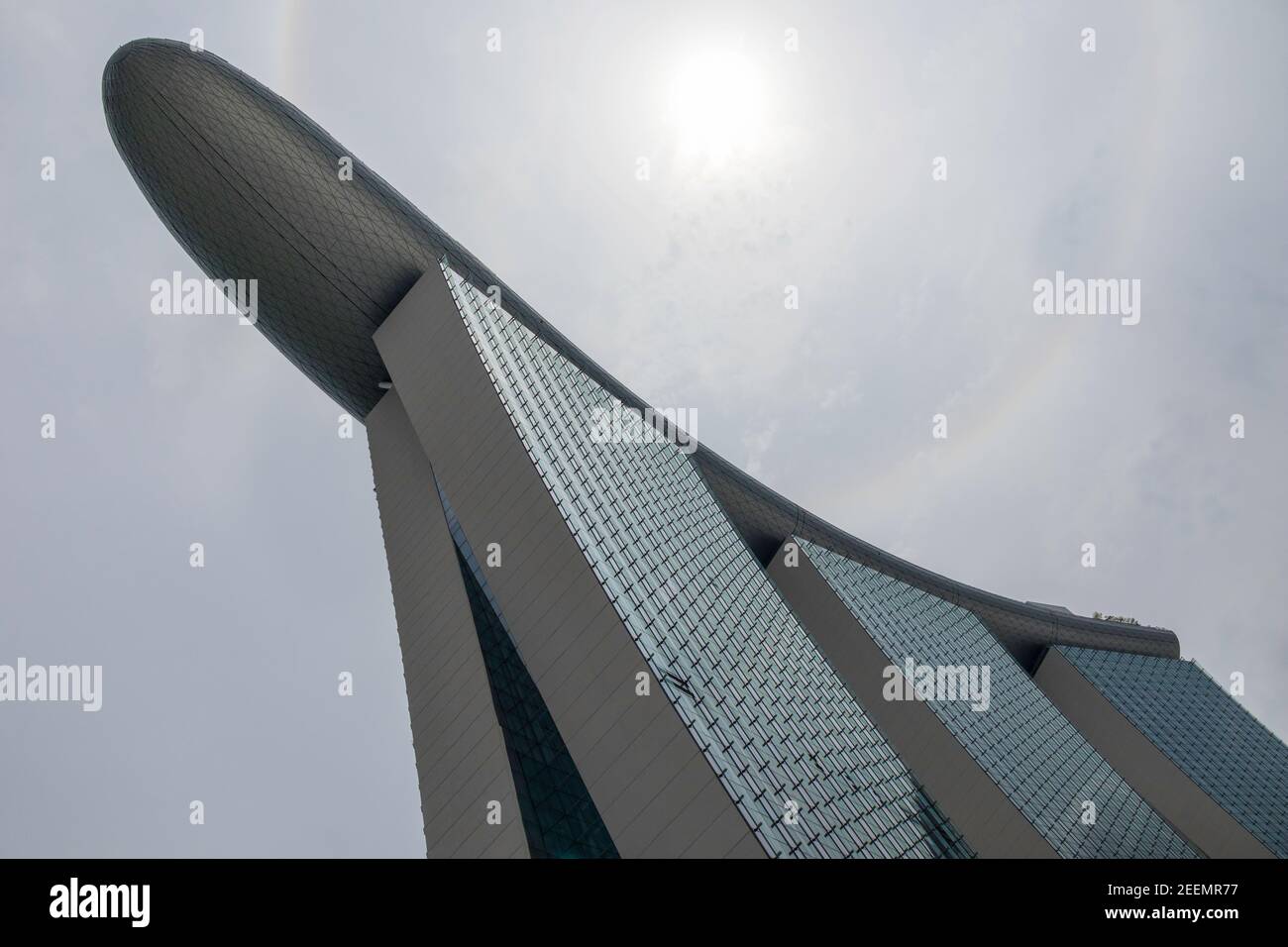 El Marina Bay Sands Hotel, Singapur, desde abajo, mostrando la forma de barco saliente de la cubierta superior contra el cielo gris pero brillante, con espacio de copia Foto de stock