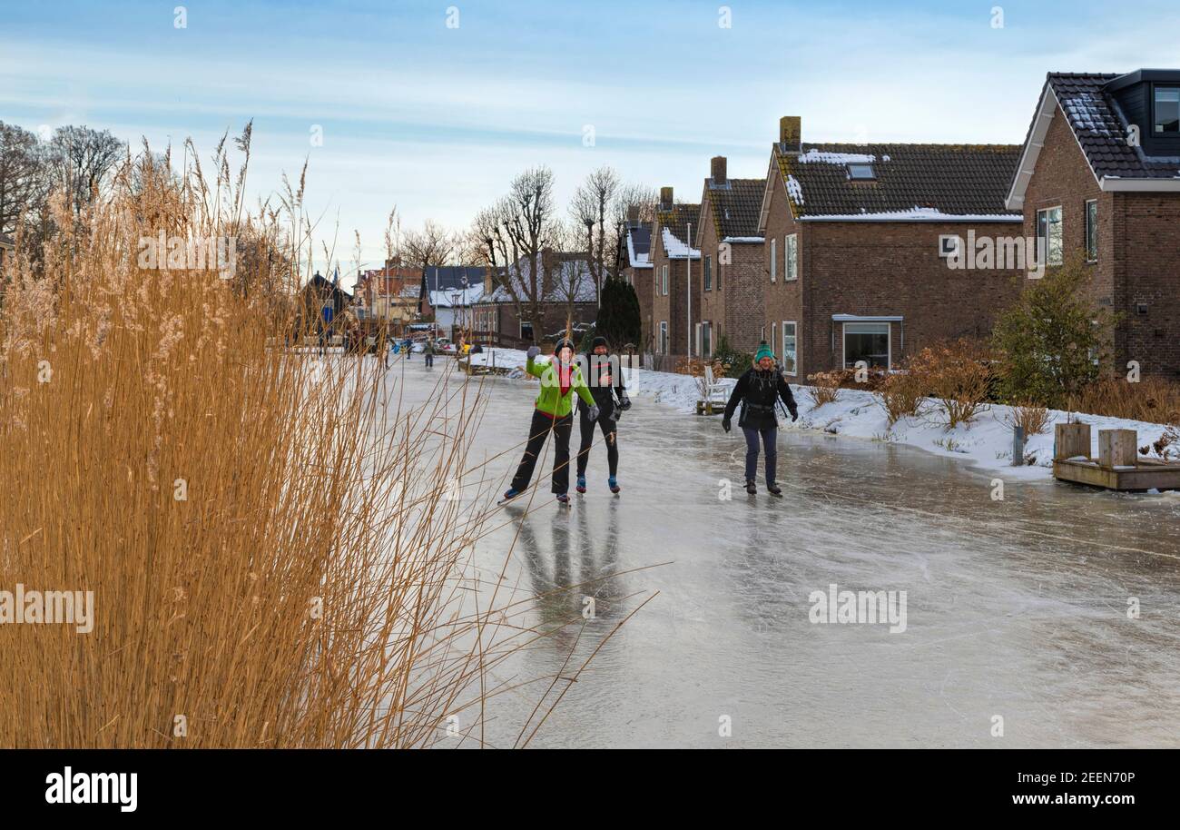 Patinadores de hielo patinando en el río congelado, Oude Ade, que recorre el pueblo de Oud Ade, Holanda del Sur, Holanda. Foto de stock