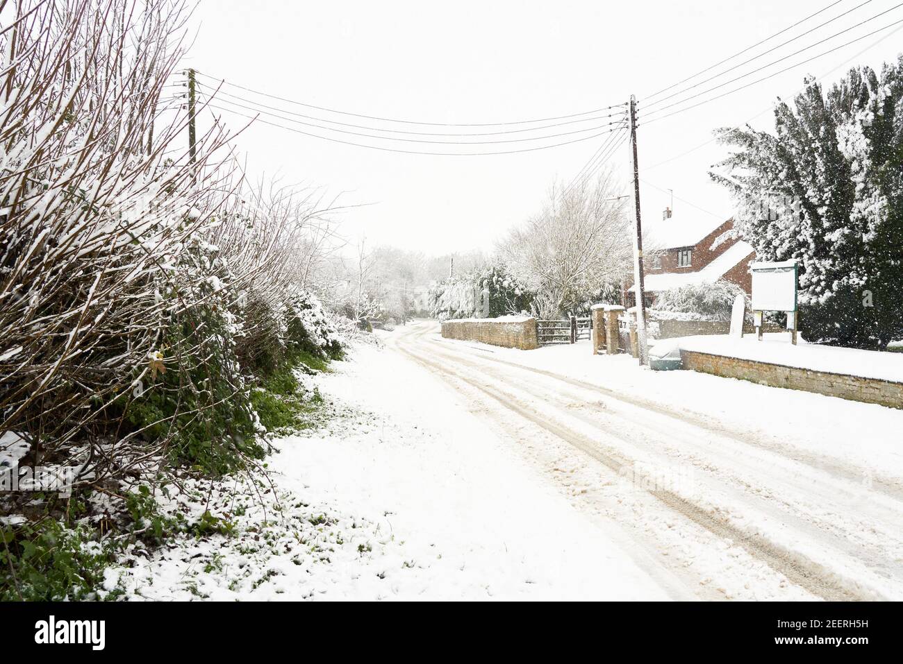 La carretera secundaria cubierta por hielo crea peligrosas condiciones de conducción durante una tormenta de nieve en invierno. Church Lane, Welby, Lincolnshire Foto de stock