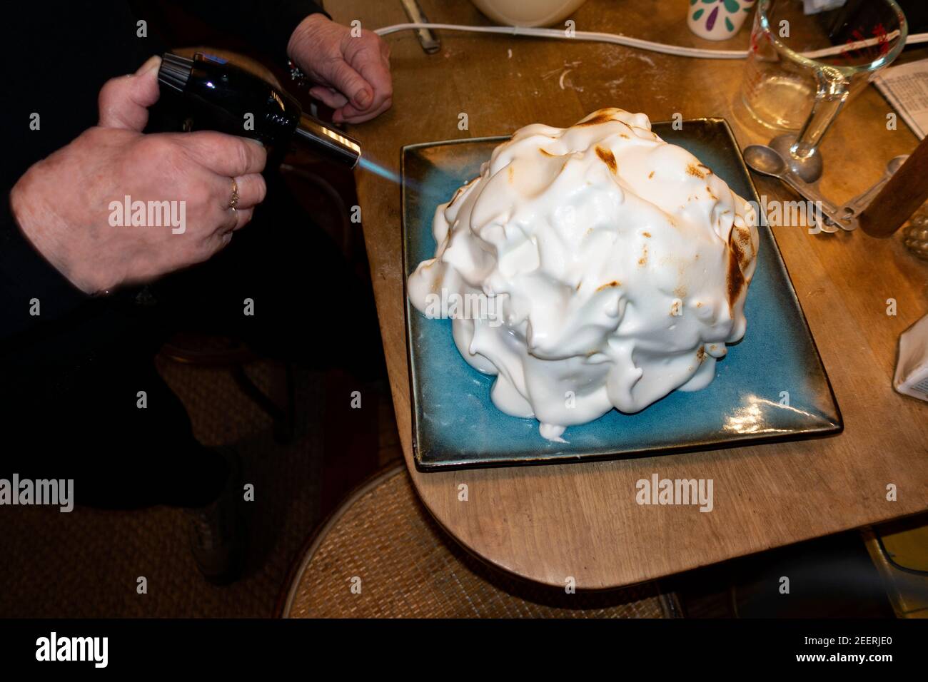 Mujer usando una antorcha de cocina para pulir el merengue en una Alaska al horno. St Paul Minnesota MN EE.UU Foto de stock