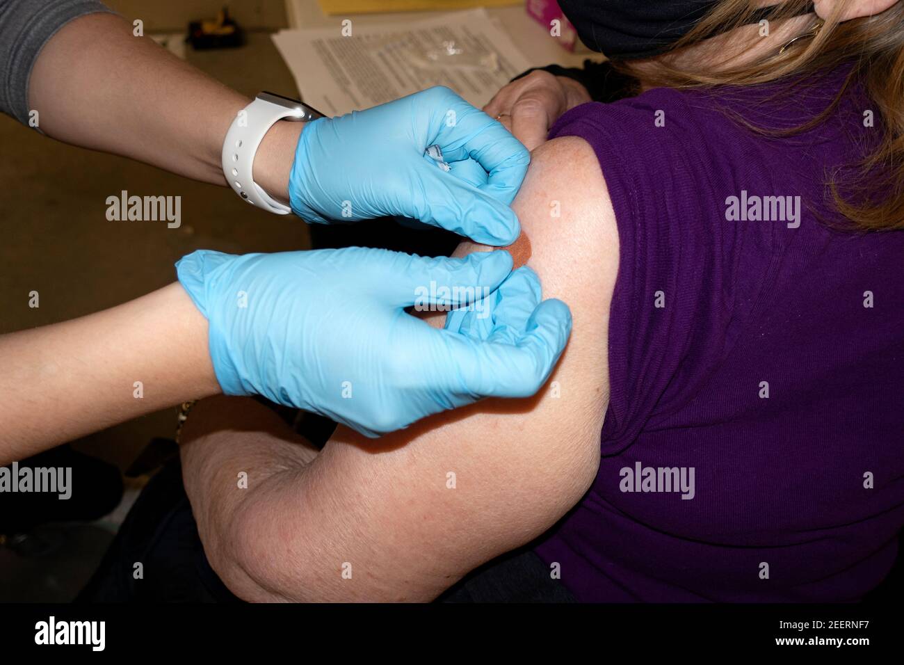 Enfermero después de inocular la vacuna Pfizer al paciente para COVID-19 colocando vendaje en el sitio. Oakdale Minnesota Minnesota, Minnesota, EE.UU Foto de stock